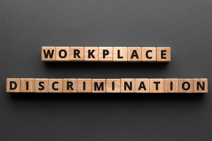 Workplace discrimination - words from wooden blocks with letters, employment discrimination legislation and issues concept, top view gray background