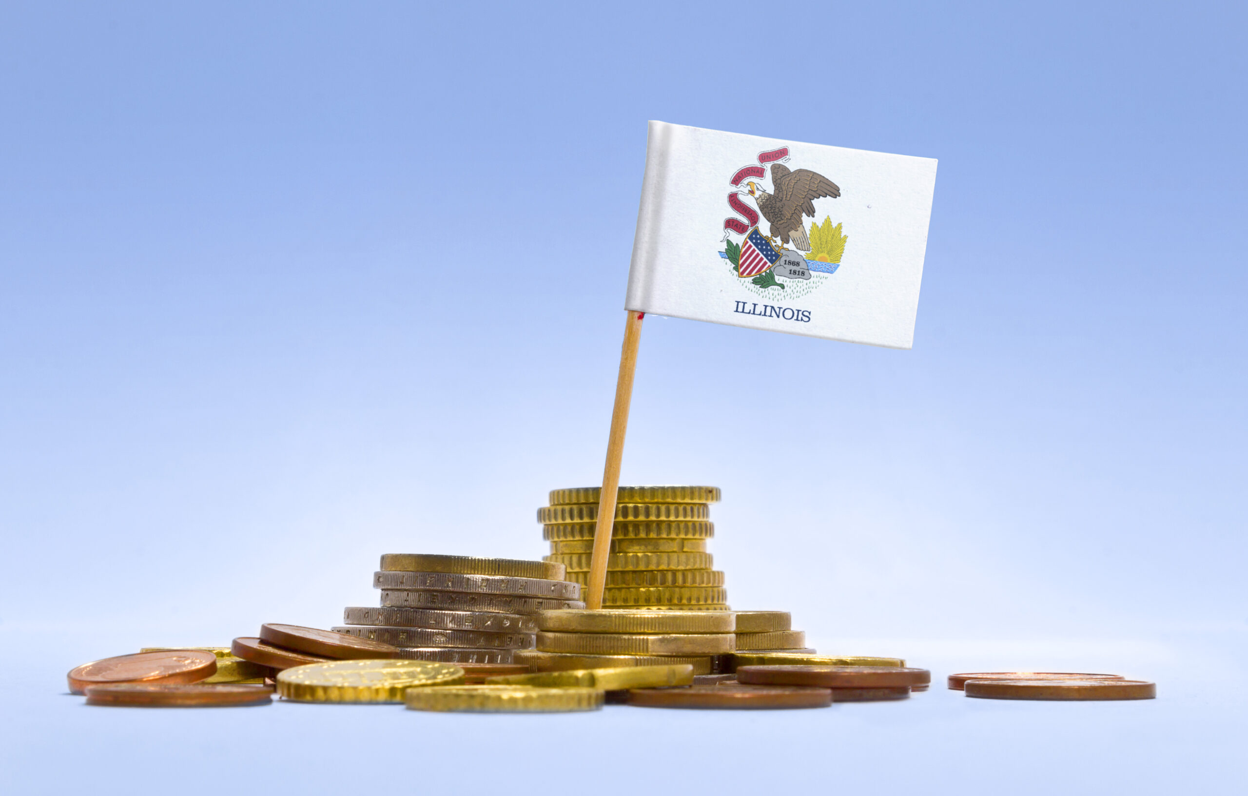 Illinois state flag on a toothpick stake planted in a pile of gold and copper coins against a blue background