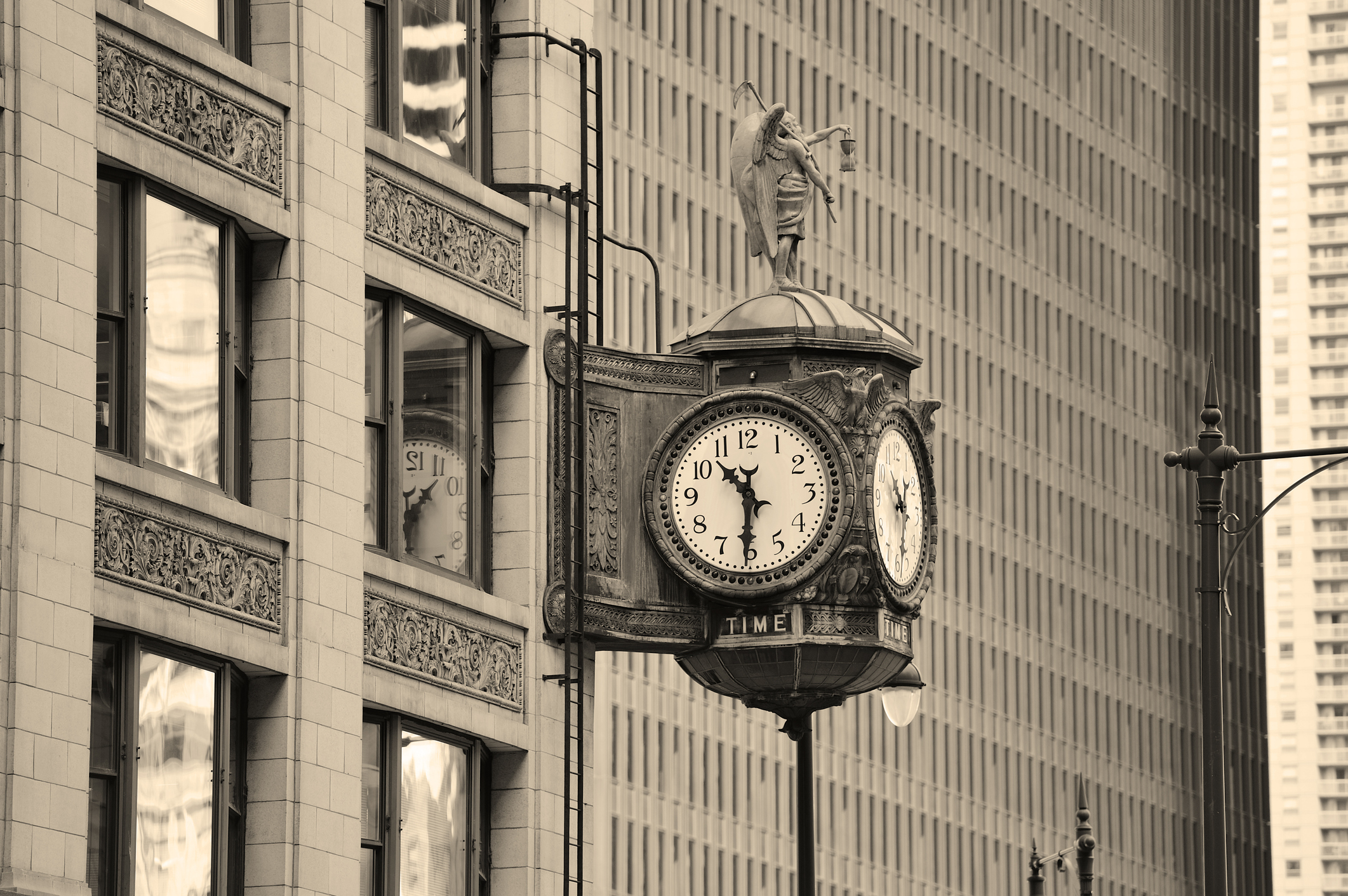 Ornate vintage street clock labeled "TIME" topped with a figure statue, mounted on a pole beside a decorative city buildin...