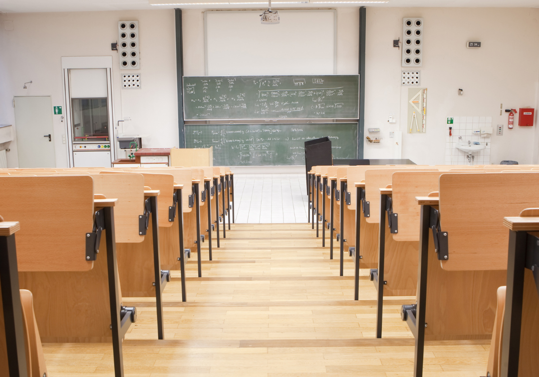 Empty university lecture hall with wooden tiered seats, chalkboard covered in equations at front, Robbins Schwartz logo at...