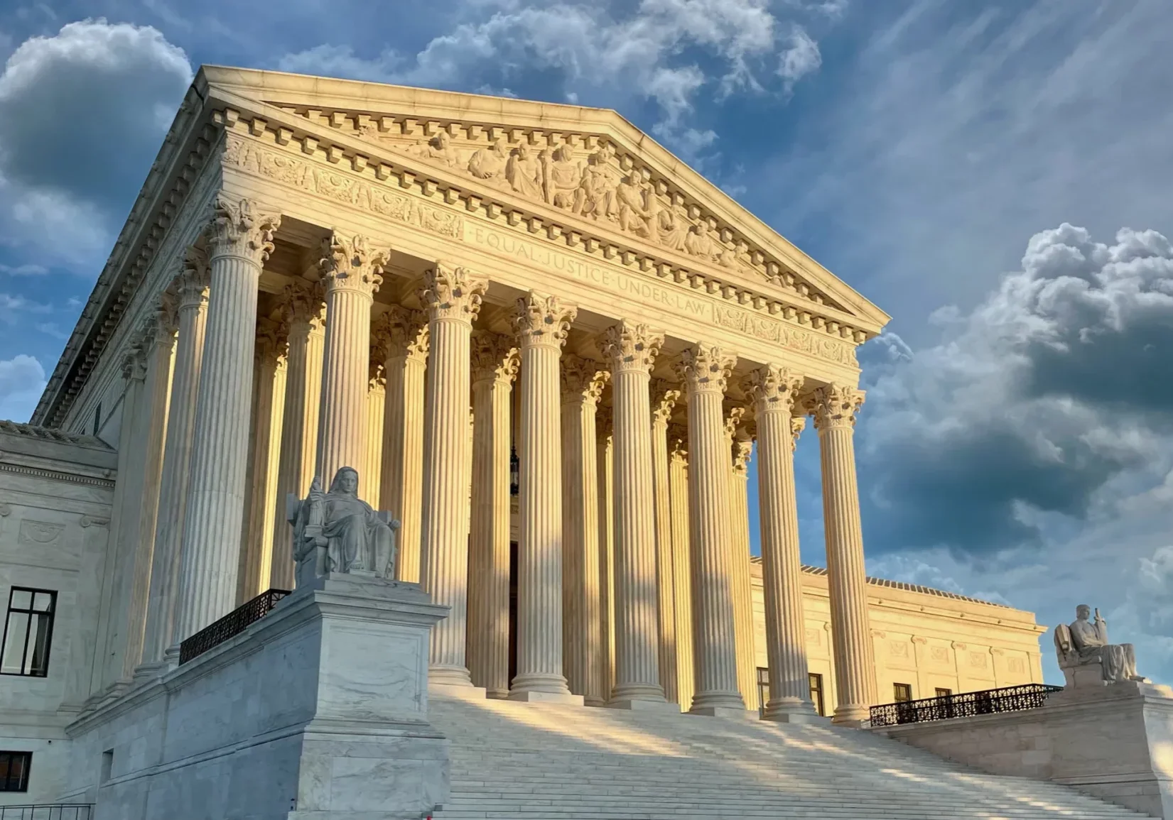 United States Supreme Court building bathed in golden sunlight, featuring marble columns, decorative frieze, and flanking ...